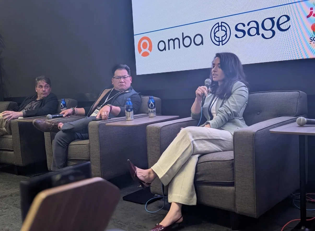 Natalyia speaking into a microphone on a panel stage