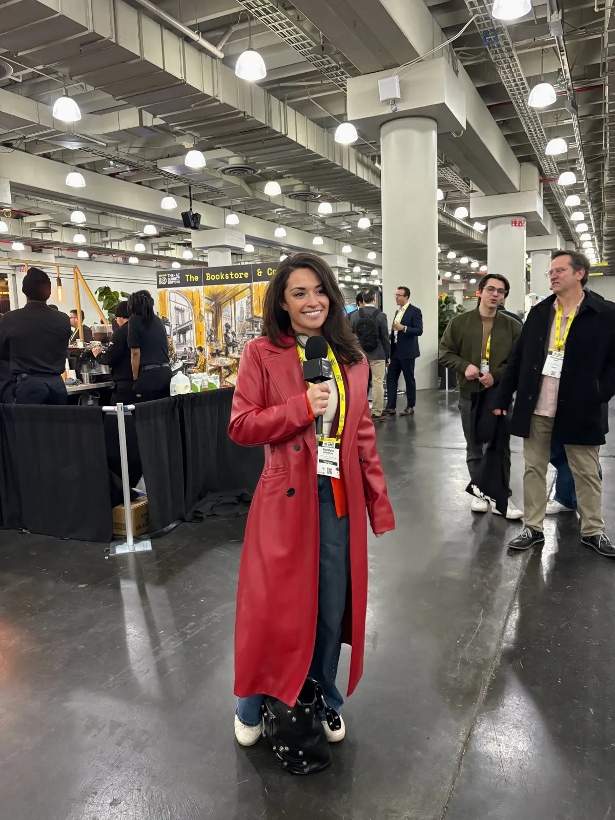 Natalyia in a red coat holding a microphone while being interviewed at The AI Summit New York
