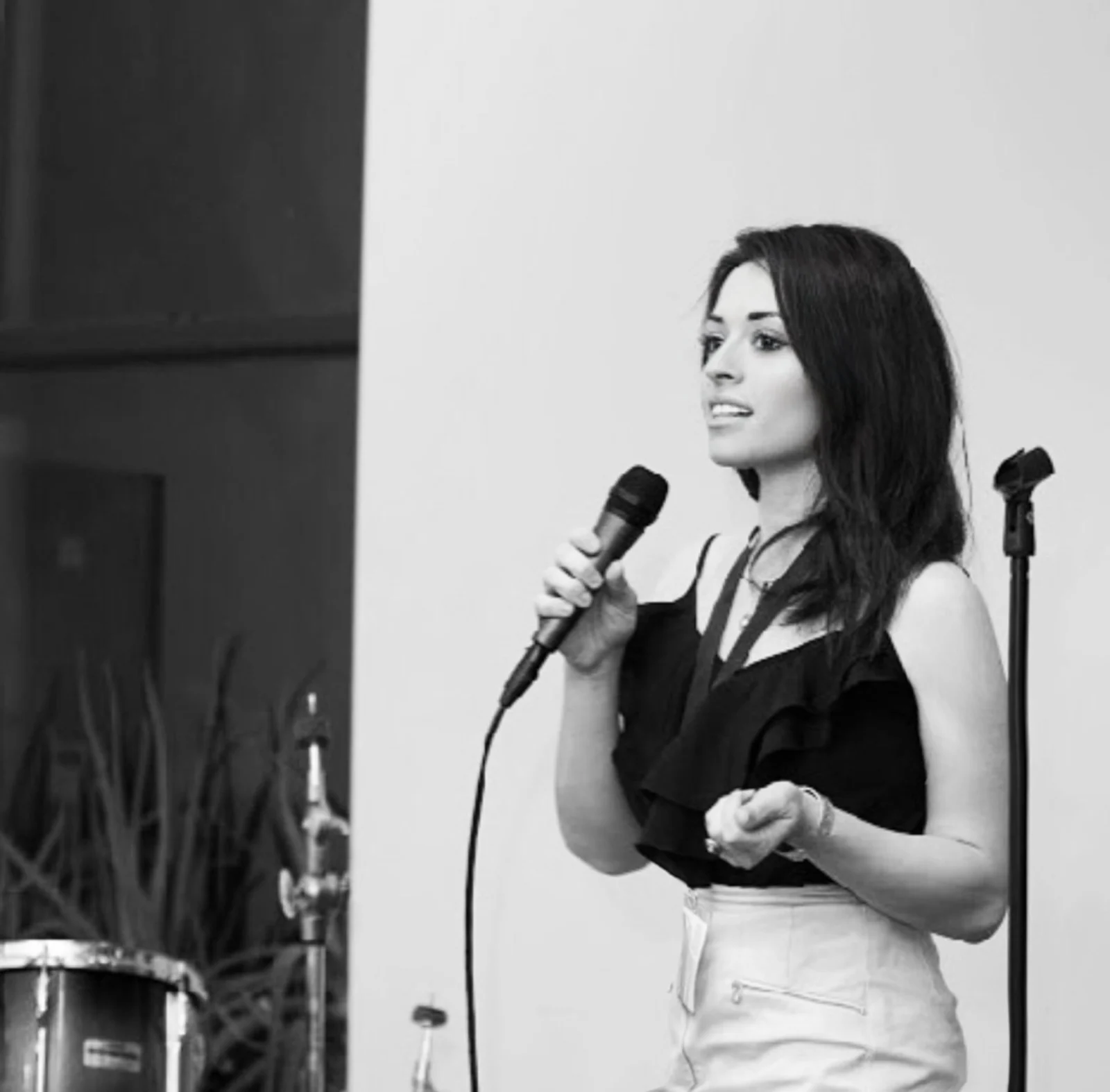 Natalyia holding a microphone while addressing a room